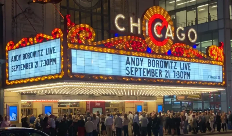 the chicago theatre lit up at night, with andy borowitz live featured on the marquis and a crowd of people waiting underneath